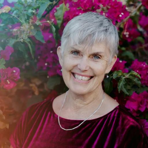 A smiling person in front of a flowering bush