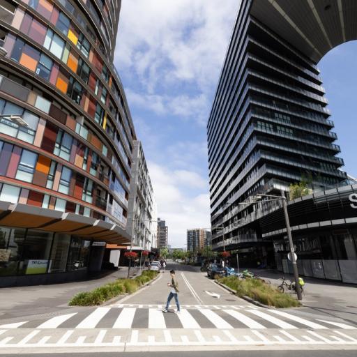 Person walking along zebra crossing between two tall buildings